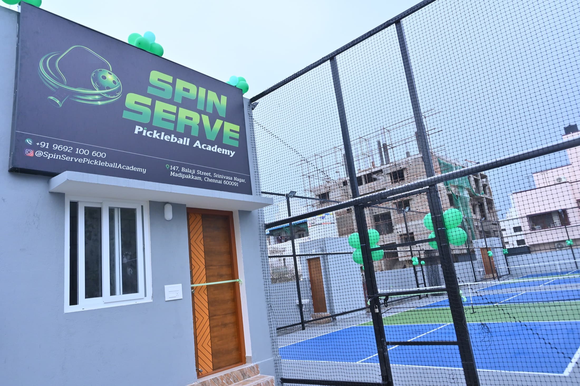 The Spin Serve Pickleball Academy signboard beside the entrance, with the courts visible through the fence